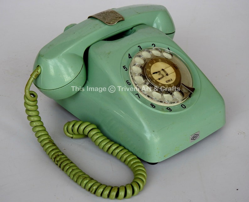 May include: A vintage green rotary dial phone with a white dial and a green coiled cord. The phone has the text "OKI" on the dial.