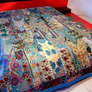 May include: A patchwork quilt with a blue border and a variety of colourful fabrics and patterns. The quilt is made of different pieces of fabric sewn together to create a unique design.