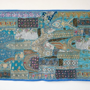 May include: A blue patchwork wall tapestry with intricate embroidery and embellishments. The tapestry features a variety of colors, including gold, silver, red, and green. It is made of a variety of fabrics, including velvet, silk, and cotton.