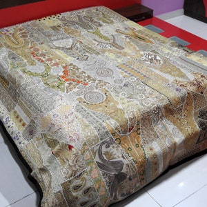 May include: A white and gold patchwork quilt with intricate embroidery and beading. The quilt is made of various fabrics and textures, creating a unique and eye-catching design.