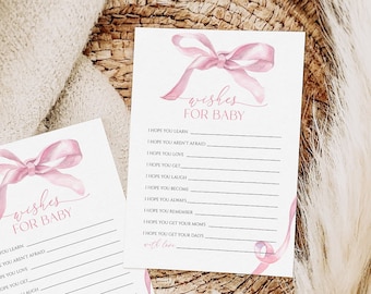 Könnte beinhalten: Zwei rosa und weiße Karten mit einem rosa Band und dem Text "wishes for baby" auf jeder Karte. Die Karten liegen in einem geflochtenen Korb mit einer weißen, flauschigen Pflanze.