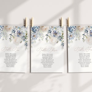 May include: Three white cards with blue floral designs and calligraphy text. The cards are labeled "Table Two", "Table Three", and "Table Four" and list names for each table.