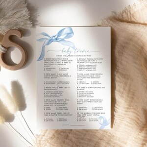 May include: A blue and white baby shower game card with the title "Baby Trivia" and questions about babies. Circle the correct answers to win.