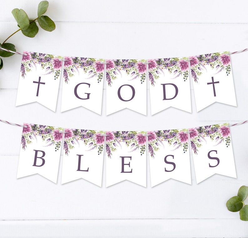 May include: A white banner with purple floral accents reads "GOD BLESS" in purple letters. The banner is strung with white twine and is perfect for a religious celebration.