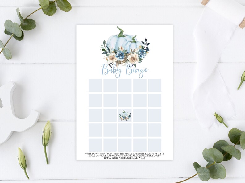 May include: A blue and white baby shower bingo card with a watercolor illustration of pumpkins and flowers. The card has the text "Baby Bingo" at the top and instructions at the bottom.