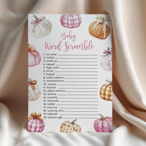 May include: A baby shower word scramble game card featuring watercolor pumpkins in shades of pink, orange, and white. The card has the text "Baby Word Scramble" and numbered lines for answers.