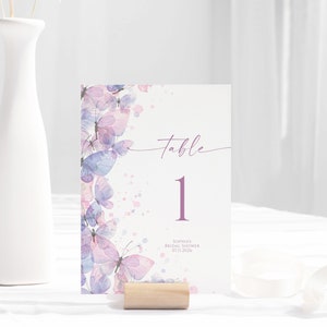 May include: A purple and pink watercolor butterfly table number card with the text "table 1" and the text "Sophia's Bridal Shower 01.21.2018".