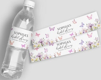 May include: Clear water bottle with a label that reads "SOPHIA'S bridal shower 07.25.2026 KEY WEST, FL." The label features watercolor butterflies and floral elements in shades of pink, purple, and white. Two additional labels are also visible.