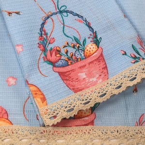 May include: Blue fabric with a white crochet trim. The fabric has a floral pattern with a basket of flowers and eggs.