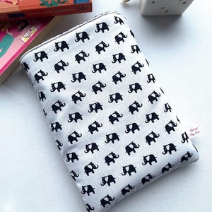 May include: A white fabric pouch with a black elephant print. The pouch has a zipper closure and a small label that says "Gorgis By Cor."