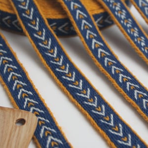 Ribete de lana tejida en tablilla. Recreación vikinga. Azul, amarillo y blanco.