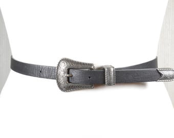 Cinturón vintage de cuero negro con hebilla plateada ornamentada, estilo vaquera occidental