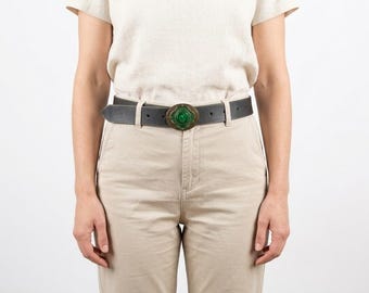 Cinturón vintage de cuero negro con hebilla de medallón de cristal verde, estilo retro western.