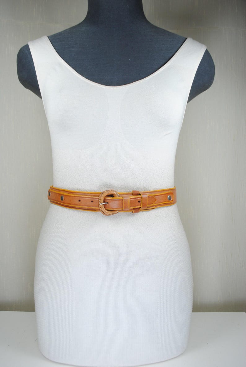 A mannequin wearing a white dress and a brown belt.