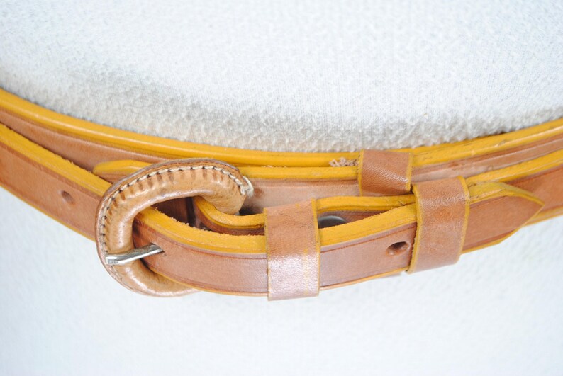 A close-up view of a leather belt with a buckle, showing the details of the belt and the buckle.