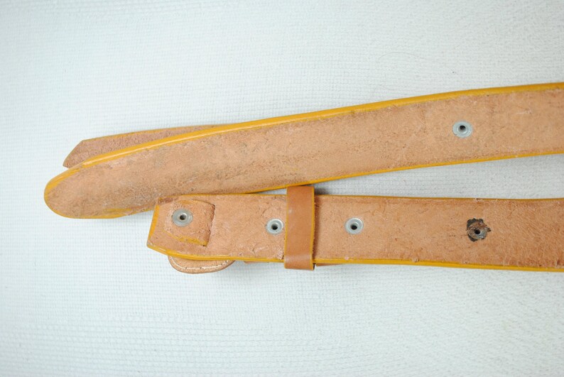 A close-up view of a leather belt with a yellow buckle, showing signs of wear and tear.