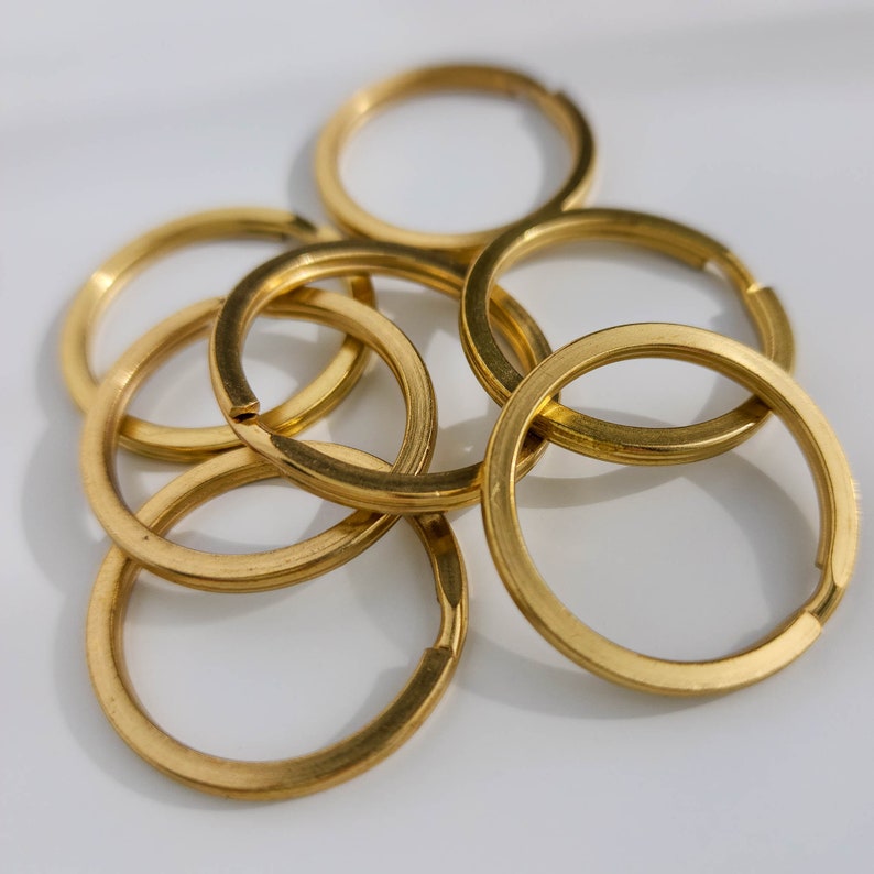 Puede incluir: Un juego de seis llaveros de metal de color dorado. Los anillos est&aacute;n entrelazados y dispuestos en una pila.