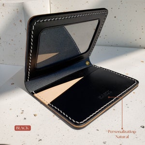 Puede incluir: Cartera de cuero negro con ventana de identificaci&oacute;n transparente y costuras blancas en contraste. La cartera tiene un interior de cuero natural y un remache dorado. La palabra "BLACK" est&aacute; impresa.