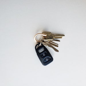 Puede incluir: Un llavero de coche negro con tres botones y un llavero de oro unido a un juego de llaves. Las llaves son doradas y tienen una variedad de formas y tama&ntilde;os.