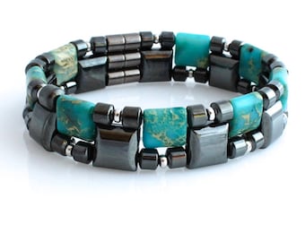 May include: A bracelet made of black and turquoise beads. The bracelet is made of two rows of beads, with the turquoise beads being larger and more prominent. The bracelet is designed to be worn on the wrist.