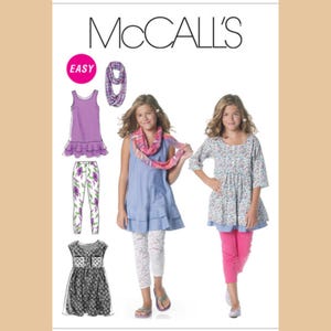 May include: McCall's sewing pattern featuring girls' clothing designs. The image shows a variety of outfits, including a purple tank top, floral leggings, a blue dress, and a floral top with pink leggings. The word "EASY" is in a pink circle.
