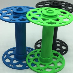 May include: Three 3D printed spools in blue, green, and black. The spools have a decorative design around the top and bottom.