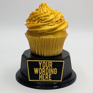 May include: Gold cupcake trophy with a black base and a plaque that says "YOUR WORDING HERE".