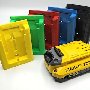 May include: A selection of brightly coloured battery holders in yellow, green, red, blue, and black. A yellow and black Stanley Fatmax V20 2.0Ah Lithium Ion battery is in the foreground. The holders are designed to secure the battery.