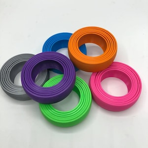 May include: Six colourful, multi-layered, round, plastic rings. The rings are stacked on top of each other in a pyramid shape. The colours of the rings are grey, purple, green, pink, orange, and blue.