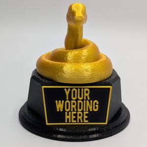 May include: A gold-coloured 3D printed trophy shaped like a snake coiled around a base. The base is black with a gold-coloured plaque that says "YOUR WORDING HERE".