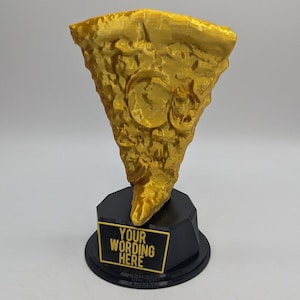 May include: A golden-colored pizza slice trophy with a textured surface, mounted on a black base. The base features a gold-bordered plaque with the text "YOUR WORDING HERE". The trophy is a unique decorative item.