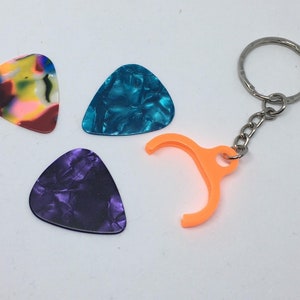 May include: Three guitar picks in different colors and patterns: multi-colored, blue, and purple. A keychain with an orange pick holder is also included.