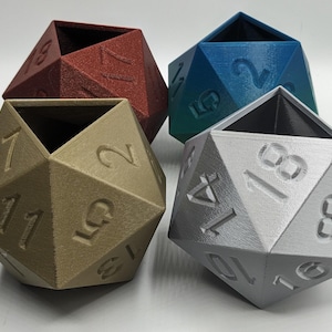 May include: Four 20-sided dice shaped planters in different colors: red, gold, blue, and silver. Each die has numbers 1 through 20 printed on the sides.