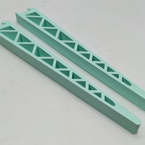 May include: Two light green plastic supports with a triangular pattern. The supports are long and narrow.