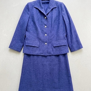 Può includere: Un completo a due pezzi composto da un blazer a maniche lunghe e una gonna abbinata in tinta unita viola. Il blazer presenta un bavero dentellato, quattro bottoni frontali e due tasche con patta. La gonna è caratterizzata da un taglio dritto.