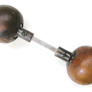 May include: A vintage door handle with two wooden, spherical knobs connected by a metal bar. The knobs are a warm brown color, and the metal components are a darker, aged metal.