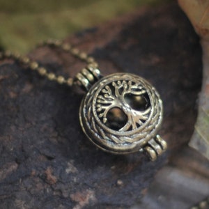 May include: A gold-toned necklace with a round pendant featuring a tree of life design. The pendant is open and has a hinged lid.