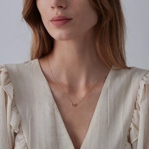 May include: A gold chain necklace with a small, delicate pendant made of multiple stacked rings.