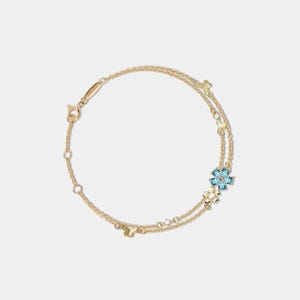 Puede incluir: Una delicada pulsera dorada con un diseño de doble cadena. Adornada con pequeños abalorios dorados y un grupo de flores de piedras preciosas azul claro. La pulsera tiene un cierre ajustable para un ajuste cómodo.