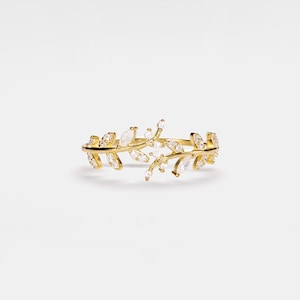 May include: A gold ring with a delicate design of intertwined branches and leaves, accented with sparkling clear stones.
