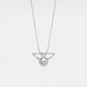 May include: A silver necklace with a pendant shaped like two angels with wings intertwined. The pendant has a small round pearl in the center and is surrounded by small clear stones.