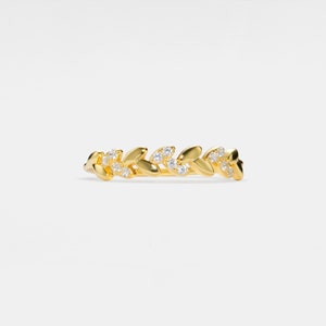 May include: A gold ring with a delicate design of leaves and small clear stones.