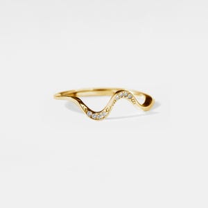 May include: A gold band ring with a wavy design and small diamonds set along the top.
