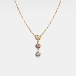 May include: A gold chain necklace with three round gemstone pendants. The top pendant is a light yellow, the middle pendant is a light purple, and the bottom pendant is a light blue.