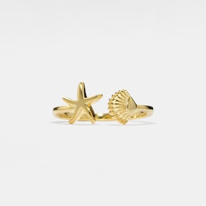 Può includere: Anello in oro con un design a forma di stella marina e conchiglia.