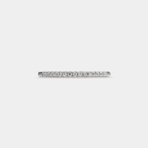 May include: A thin silver band with a row of small, clear diamonds set around the entire band.