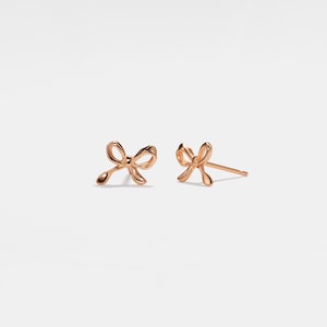 May include: A pair of gold-toned bow-shaped stud earrings.