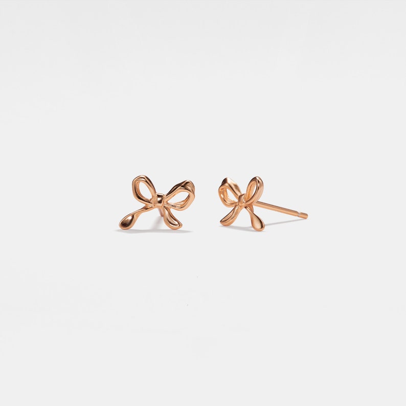 May include: A pair of gold-toned bow-shaped stud earrings.
