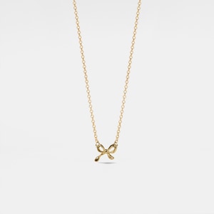 May include: A gold chain necklace with a small, delicate bow pendant.