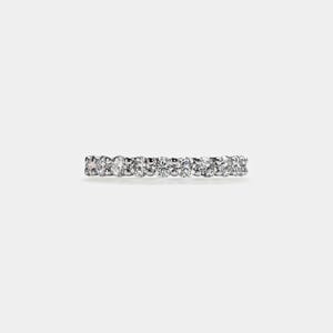 Puede incluir: Un anillo de banda de plata con una fila de pequeños diamantes transparentes.